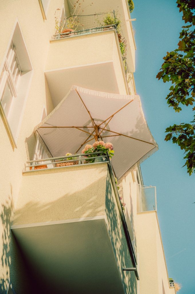 Balcony with umbrella and plants against blue sky